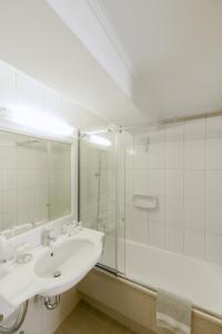 a white bathroom with a sink and a shower at Kastello Hotel in Nafplio