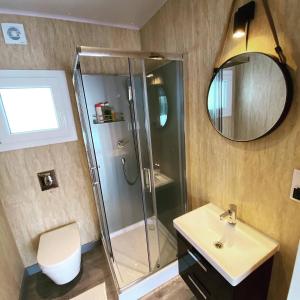 y baño con ducha, lavabo y espejo. en Małe Formy - drewniany domek w górach z balią en Kamienna Góra