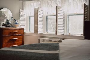 een slaapkamer met witte luiken en een bed bij Hill Road Manor Bed & Breakfast in Grand Falls -Windsor