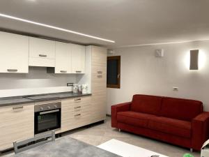 a living room with a red couch and a kitchen at Appartamento Tre Archi con corte privata in Venice