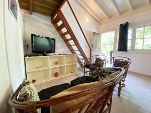 sala de estar con TV y algunas sillas en Casa Vento Leste, en Ilhabela