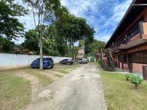 Dos coches estacionados en un estacionamiento al lado de un edificio. en Casa Vento Leste, en Ilhabela