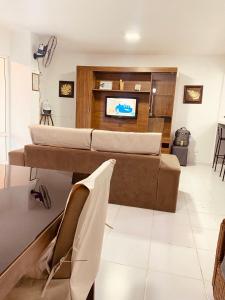 a living room with a couch and a tv at Apartamento até 10 pessoas na enseada Guarujá em condomínio clube praia piscinas salão jogos quadra futebol campo parquinho brinquedos Wi-fi Home office in Guarujá