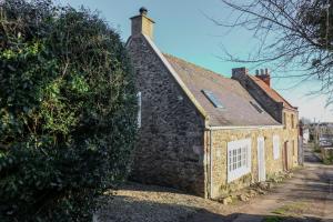 an old stone building with a window and a hedge at 15 Bogan in Eyemouth