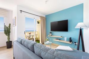 Sala de estar azul con sofá y TV en Candelaria playa TENERIFE, en Candelaria