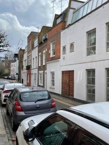 rząd zaparkowanych samochodów na ulicy miejskiej w obiekcie Stylish 3 bedroom town house w Londynie