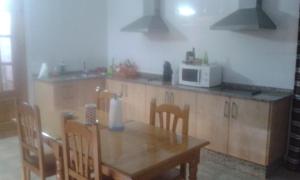 a kitchen with a wooden table and a microwave at Hostal El Arrecife in Sorbas
