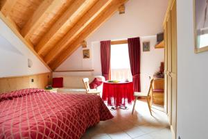 una camera con letto rosso e tavolo di Hotel Cevedale a Santa Caterina Valfurva