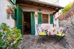 tavolo e sedie di fronte a una casa con persiane verdi di Appartamento Pomonte a Pomonte