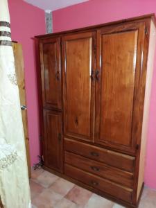a wooden cabinet in a room with a pink wall at CASTLE VIEW VILLA in Diamond