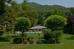 un giardino con tavolo, ombrellone e alberi di Landhaus Hindenburg a Bad Gleichenberg