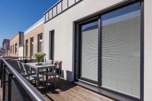 d'un balcon avec une table, des chaises et une fenêtre. dans l'établissement Robbenloft, à Norderney