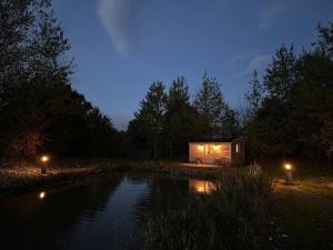 a small cabin next to a pond at night at Luxury Shepherds Hut - The Sweet Pea by the lake in York