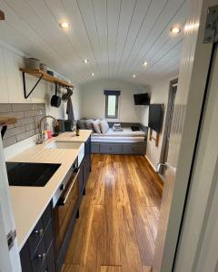 uma cozinha com um lavatório e um sofá ao fundo em Luxury Shepherds Hut - The Sweet Pea by the lake em York