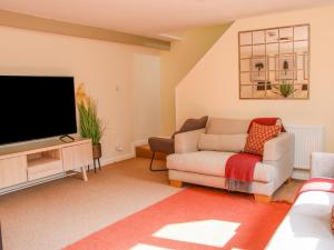 a living room with a couch and a flat screen tv at Coach House at Old Vicarage in Telford