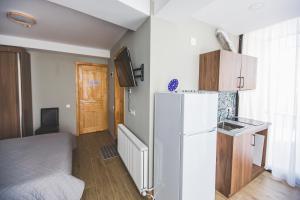 a small kitchen with a white refrigerator and a bed at Perfect studio near Didveli ski area in Bakuriani