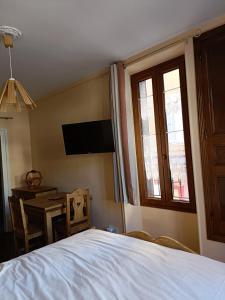 a bedroom with a bed and a table and a television at Barcelonnette studio 2 personnes in Barcelonnette