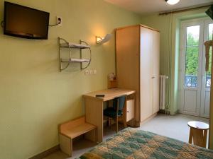 - une chambre avec un bureau, un lit et une télévision dans l'établissement Les Charmilles, à Poligny