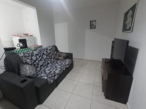 a living room with a black couch and a tv at Apto Agua Marinha in Campos dos Goytacazes