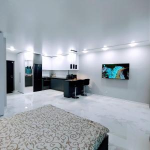 een grote witte kamer met een bed en een keuken bij VIP Apartment near Center in Lviv