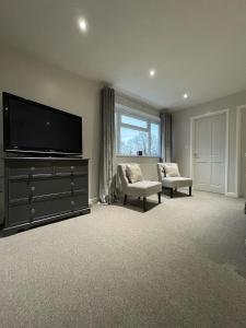 a living room with a flat screen tv and two chairs at Bricket House in Great Malvern