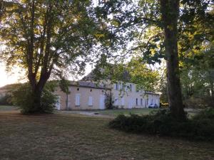 une maison blanche avec des arbres devant elle dans l'établissement La Sabatière, à Bergerac