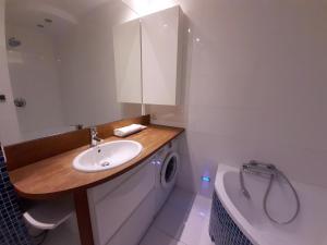 a bathroom with a sink and a washing machine and a tub at Apartament Rokosowska in Warsaw