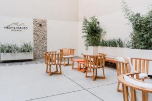 um pátio com cadeiras e mesas de madeira e plantas em Mediterráneo Hotel y Spa em Rosário