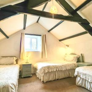 Pokój na poddaszu z 2 łóżkami i oknem w obiekcie Ta Mill Holiday Cottages & Lodges - Forge Cottage w mieście Launceston