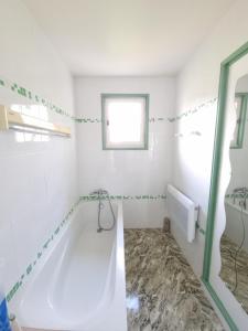 a white bathroom with a tub and a window at villa relax in Ascain