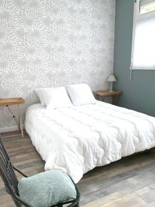 una camera con un letto bianco e una sedia di Douceur Marine a Cancale