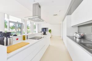 a white kitchen with white counters and windows at Elegant 2+1 BR with Fantastic Views of Ain Dubai in Dubai