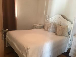 a bedroom with a white bed with white sheets and pillows at Casinha da Vila in Arcos de Valdevez