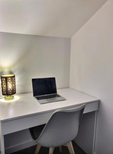 einen Laptop auf einem Schreibtisch mit einer Lampe in der Unterkunft Superbe, T2 élégant, Neuf, Parking in Gerde