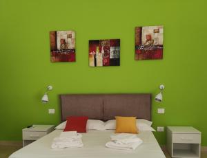 um quarto verde com uma cama com quatro fotografias na parede em LE GRAVINELLE em Ruvo di Puglia