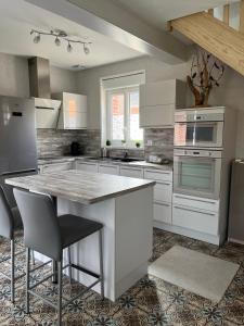 een keuken met witte kasten en een tafel met stoelen bij Gîte avec piscine in Lestrem