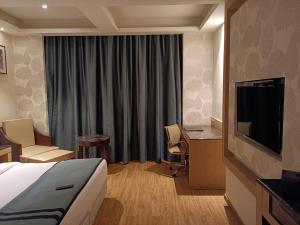 a hotel room with a bed and a flat screen tv at HOTEL V in Lucknow