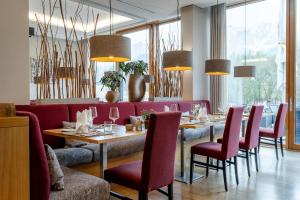 a dining room with a table and red chairs at Klosterhof – Alpine Hideaway & Spa in Bad Reichenhall