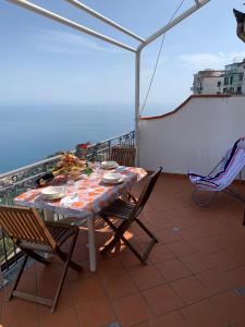 una mesa y sillas en un balcón con vistas al océano en DONNA CONCETTA HOUSE en Ravello