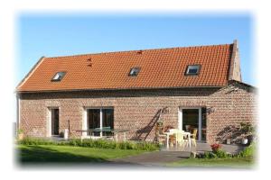 een stenen huis met een tafel en stoelen ervoor bij LE DOMAINE DES SAULES in Richebourg