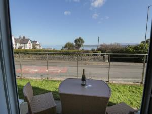 a bottle of wine sitting on a table in front of a window at Benllech Coastal Retreat in Benllech