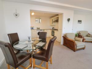 cocina y comedor con mesa de cristal y sillas en Benllech Coastal Retreat, en Benllech