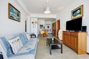 a living room with a blue couch and a flat screen tv at Frente Mar in Portimão