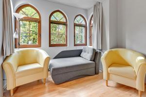 two chairs and a couch in a room with windows at Apartamenty Zacisze & by Noclegi Renters in Sopot