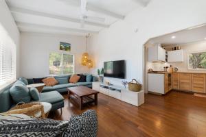 a living room with a blue couch and a tv at Peaceful and Renovated Original Beach House with Sweeping Views of Gracetown in Gracetown