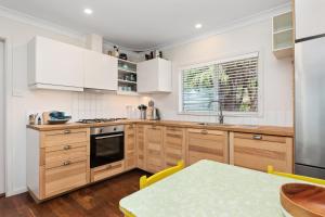 a kitchen with wooden cabinets and a table and a window at Peaceful and Renovated Original Beach House with Sweeping Views of Gracetown in Gracetown +11 photos