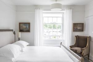 a white bedroom with two beds and a window at Antonia's Pearls in St Austell