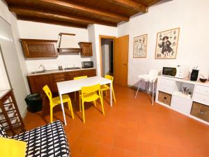 een keuken met een witte tafel en gele stoelen bij Casa Vacanze di Arlecchino in San Giovanni Bianco