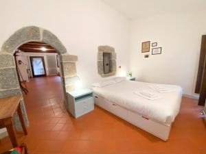 1 dormitorio con cama blanca y pared de piedra en Casa Vacanze di Arlecchino, en San Giovanni Bianco