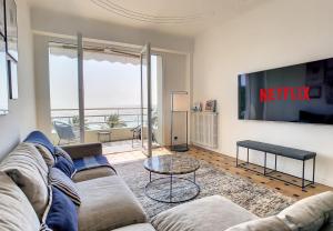 ein Wohnzimmer mit einem Sofa und einem TV in der Unterkunft Nestor&Jeeves - BLUE PROMENADE - Sea front - Central - Luxe in Nizza